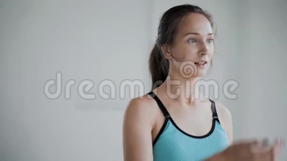 疲惫的年轻白种人女孩在白色背景下进行有效的锻炼后前额擦汗微笑笑视频的预览图