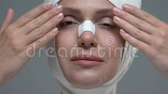 女人在张开眼睛的脸上用弹力绷带包扎享受整形手术的结果视频的预览图