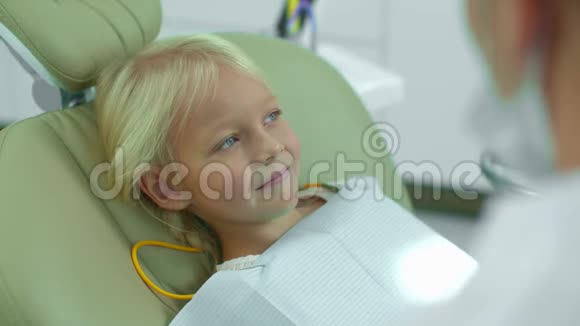 牙医在女孩的嘴上放了一盏灯看着她的牙齿视频的预览图
