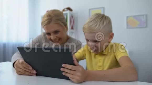 快乐的母子在平板电脑上玩游戏信任的关系消遣视频的预览图