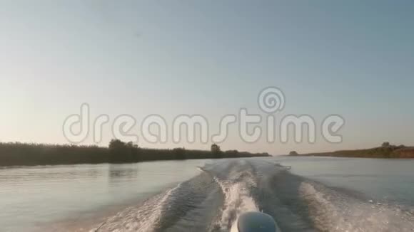 航行时摩托艇留下的河水痕迹柔和的晚光干燥的芦苇海岸视频的预览图