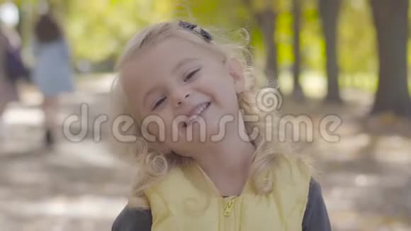 一个金发棕色眼睛笑着的漂亮小女孩的肖像可爱的白种人孩子在秋天玩得很开心视频的预览图