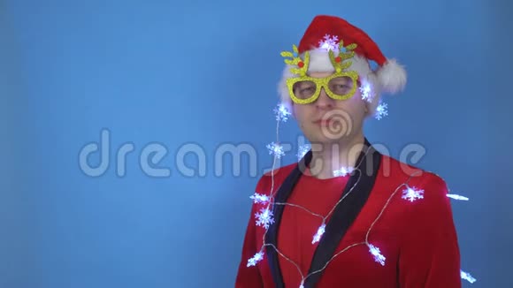 年轻的白种人穿着圣诞老人服装和新年眼镜看着相机文本位置复制空间视频的预览图