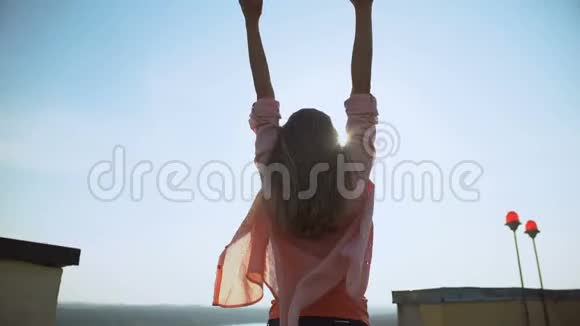 有灵感的女人在屋顶举起双手开始新的一天早晨的美丽视频的预览图