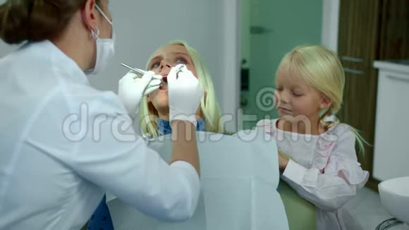 牙医看女人的牙齿女儿和她坐在一起视频的预览图