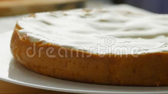 关闭视野女人在烤好的面团上撒奶油女性手在蛋糕上用勺子倒白色奶油视频的预览图