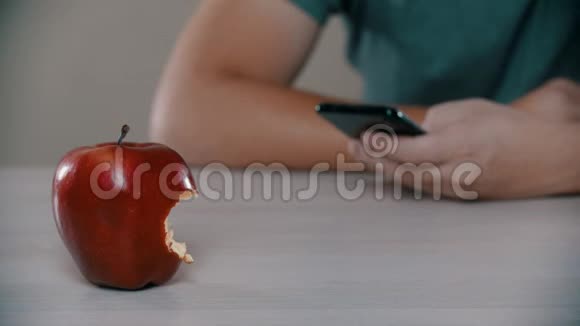 一个男人正在看一个被咬的苹果旁边的电话视频的预览图