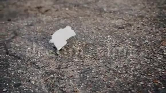 一张白色的餐巾纸卷过一块空地上的沥青美丽的慢动作图像视频的预览图