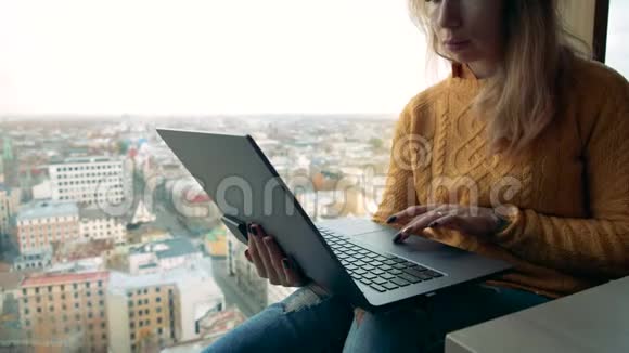 一个年轻的女人拿着一台笔记本电脑对着城市的景色年轻的女性自由职业者使用笔记本电脑视频的预览图
