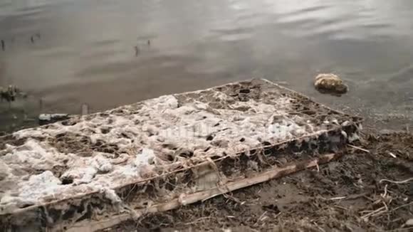 一张旧床垫躺在河岸上废弃物品视频的预览图