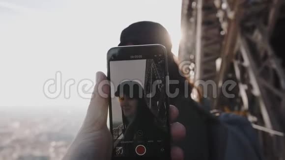 男手正拿着智能手机在埃菲尔铁塔上拍摄快乐的微笑女人浪漫与科技慢动作视频的预览图