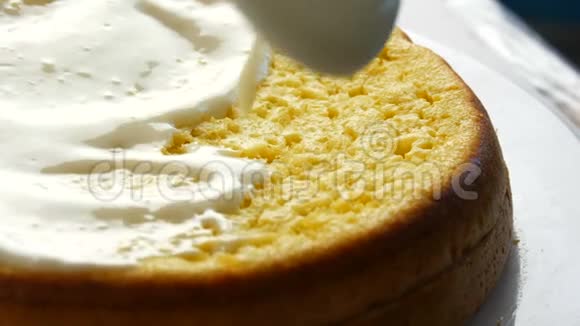 女人在烤好的面团上撒奶油女人用勺子在蛋糕上倒入白色奶油然后开始散开视频的预览图