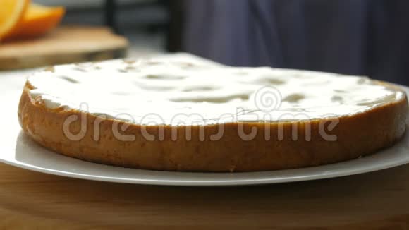 女人在烤好的面团上撒奶油女人用勺子在蛋糕上倒入白色奶油然后开始散开视频的预览图