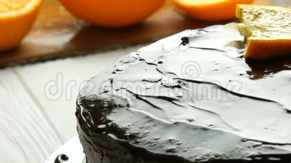 自制巧克力蛋糕加糖霜女人的手把橙汁放在白色厨房旁边视频的预览图