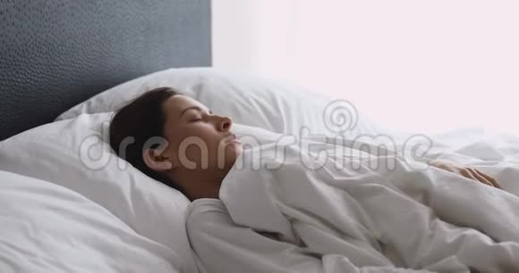 生病的年轻女人醒来坐在床上感觉背痛视频的预览图