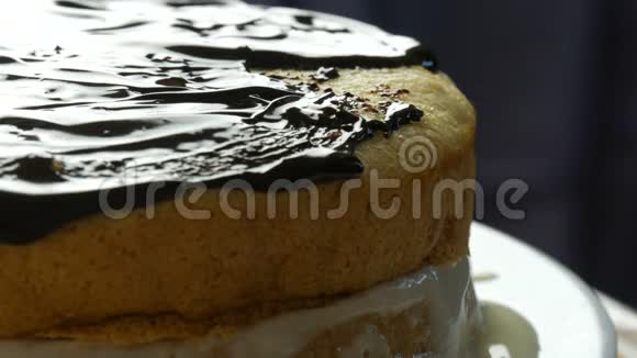 关闭视野女人在海绵蛋糕上撒了一层巧克力釉女性用勺子在蛋糕上倒入奶油视频的预览图