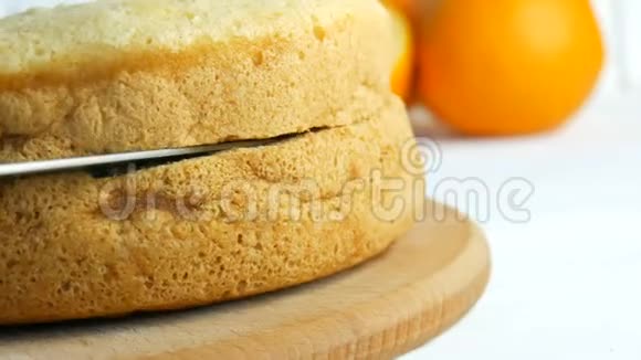 面包师的手拿着刀在厨房里切一块橙色饼干或海绵蛋糕面团做点甜的视频的预览图