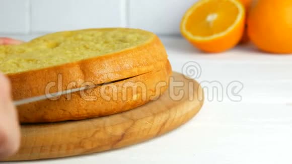 面包师的手拿着刀在厨房里切一块橙色饼干或海绵蛋糕面团做点甜的视频的预览图