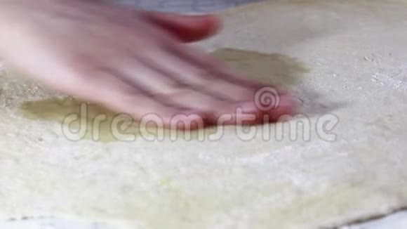 一个女人手在酵母面团上涂抹植物油视频的预览图
