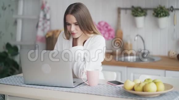 年轻妇女使用笔记本电脑在家工作喝茶自由职业者视频的预览图