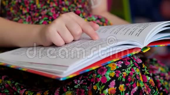 穿着五颜六色衣服的小女孩正在看书孩子学会阅读视频的预览图