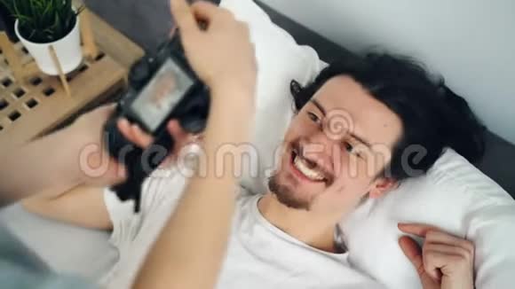 性格开朗的男生在家里摆着相机在床上笑着玩视频的预览图