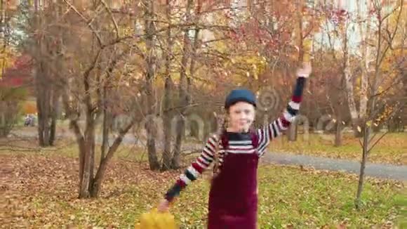 快乐的少女在城市公园手里拿着秋叶奔跑快乐的女孩在城市度过一个愉快的秋假视频的预览图