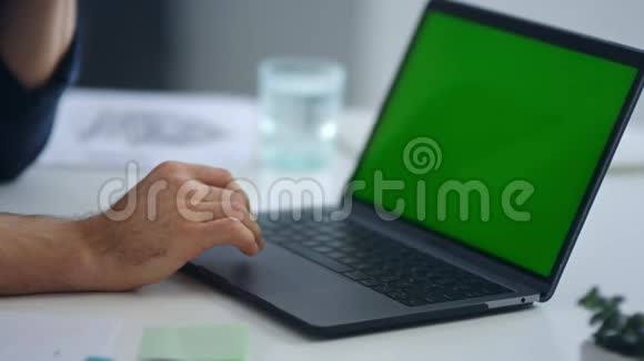 男人用绿色屏幕在笔记本电脑上打字商人手里拿着上网视频的预览图