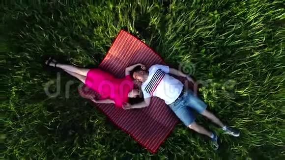 一对相爱的夫妇躺在森林里草地上从上面看到的视频的预览图