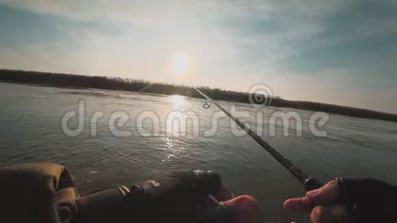 日落时分一只垂钓者从美丽的河上的一条船上旋转捕食的鱼视频的预览图