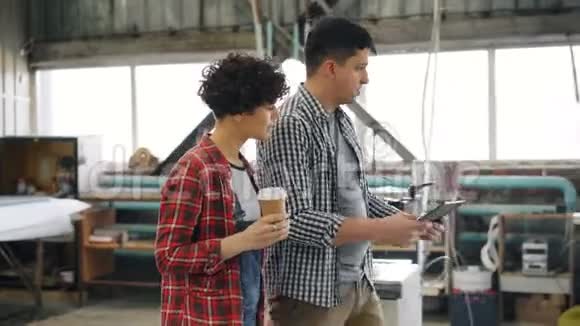 工人在木工车间说话男人用平板电脑女孩喝咖啡视频的预览图