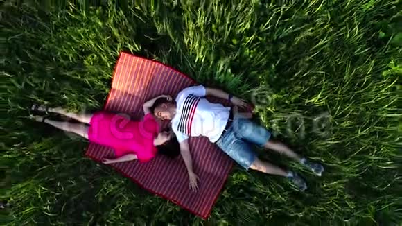 俯视着一对相爱的夫妇躺在草地上互相看着从无人机上看视频的预览图