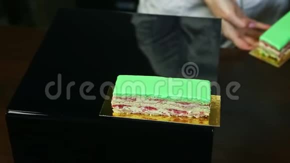 糖果师将一个接一个的三份奶油分层蛋糕与绿色釉视频的预览图