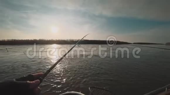 日落时分垂钓者从美丽的河上的一条船上旋转捕食的鱼视频的预览图