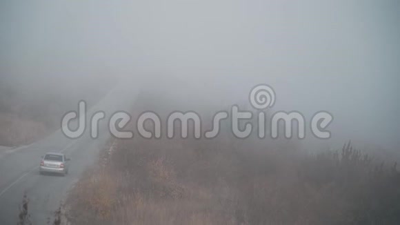 雾笼罩着群山之间的道路汽车在那里行驶视频的预览图