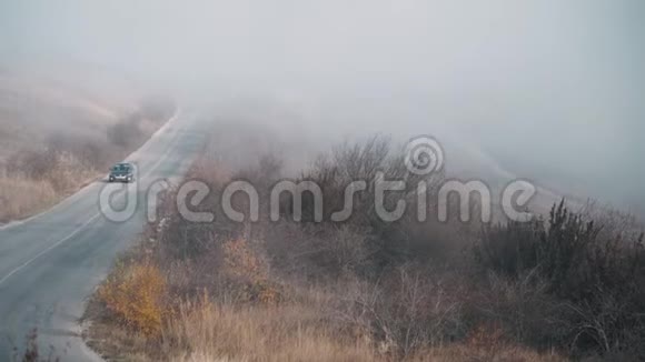 浓雾笼罩着汽车行驶的群山之间的道路视频的预览图