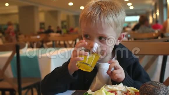 一个小快乐的情绪男孩的特写镜头喝果汁在餐馆吃饭视频的预览图
