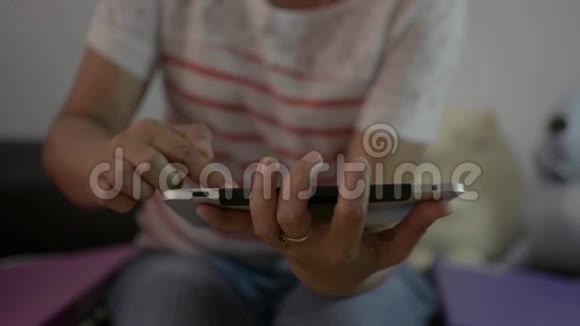 女人坐在客厅里用数字平板电脑在家里在线观看社交视频的预览图