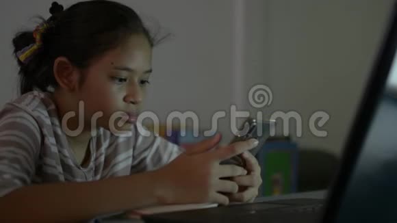 亚洲可爱的女孩穿着休闲装在做作业时使用手机在线交流视频的预览图