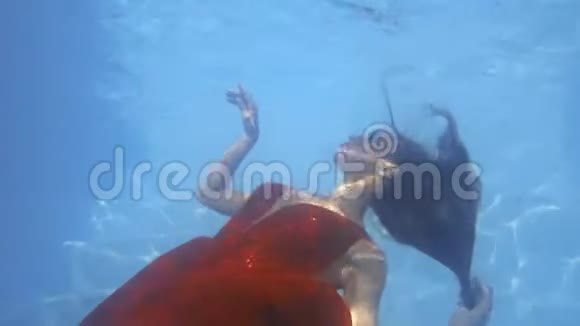美丽的红衣女子漂浮在水下触摸水面4K视频的预览图