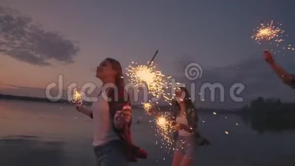 一群男男女女的朋友在海滩上快乐地奔跑着用火花和烟花庆祝节日视频的预览图