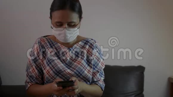 女士戴着防护面罩在手机上发短信以便在网上社交和聊天视频的预览图