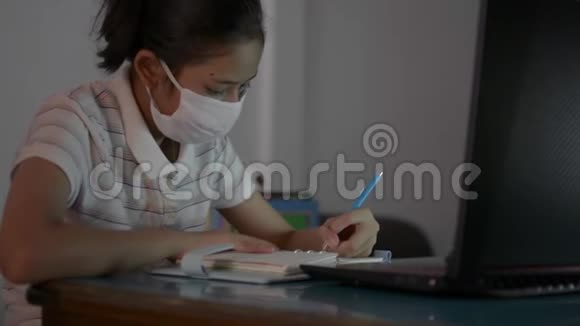 亚洲可爱的女孩戴着防护面具在COVID19大流行情况下从家里带着视频通话学习视频的预览图