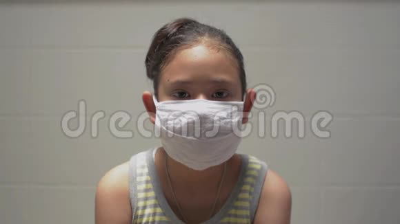 肖像亚洲可爱女孩在家期间戴着保护面具女少年展现自己的实力看着镜头视频的预览图