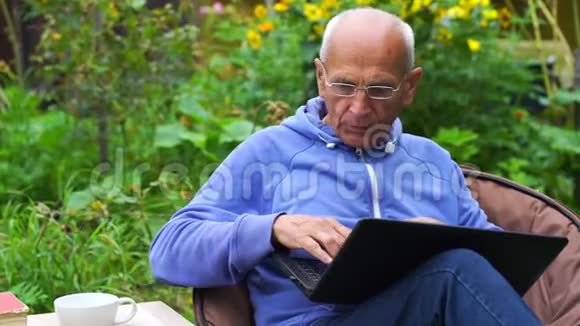 戴眼镜的高级绅士在花园里做笔记本视频的预览图