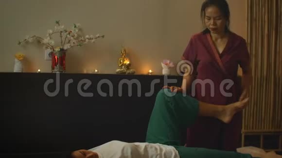 亚洲人用泰国的民族服装做按摩欧洲的亚洲水疗沙龙年轻的白种人女性放松视频的预览图