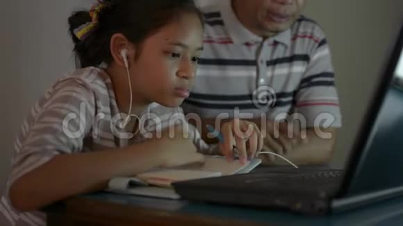 亚洲可爱的女孩与她的父亲使用笔记本电脑在线上课期间做家庭作业视频的预览图
