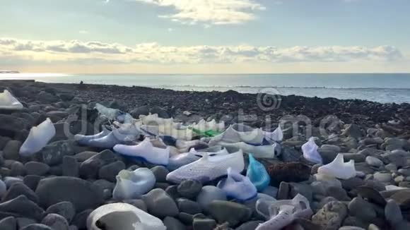 污染的海岸海滩上的垃圾空塑料瓶橡胶鞋视频的预览图