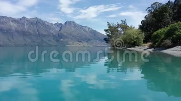 阳光明媚的一天一棵绿树淹没在清澈的蓝色湖泊中群山环绕视频的预览图