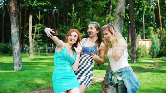 霍利的三位年轻女性在智能手机上画了一张拥抱和欢笑的自拍照片视频的预览图
